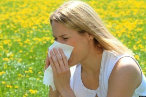 Woman sitting in meadow and blowing nose