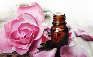 Essential oil with rose petals on wooden background