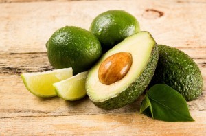 healthy food concept - avocado and lime slices on wooden background