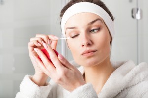 Young woman in robe removing eyes make-up